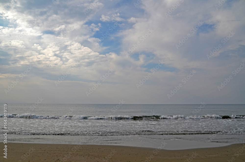 Calm Sea with Cloudy Sky. A calm sea with gentle waves rolling onto a sandy beach under a beautiful cloudy sky. The horizon line is visible, creating a peaceful and serene landscape, Cyprus Calm Sea with Cloudy Sky. A calm sea with gentle waves rolling onto a sandy beach under a beautiful cloudy sky. The horizon line is visible, creating a peaceful and serene landscape, Cyprus