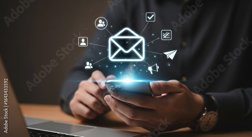 Photo of a person uses a smartphone to send and receive digital communications, with glowing icons representing email, social media, and notifications