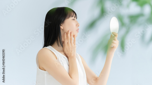 鏡で肌をチェックする女性