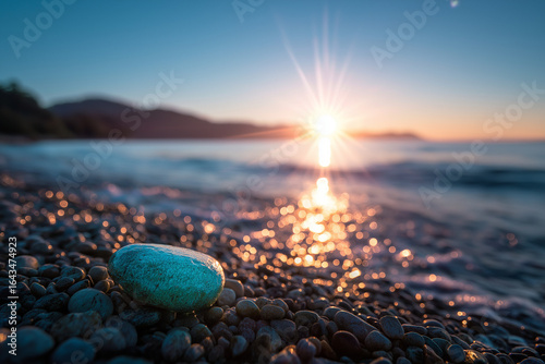 Sunset over ocean shoreline with pebbles and sunlight