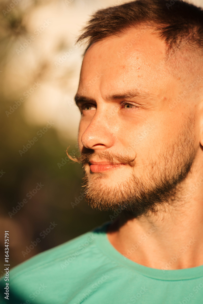 Fototapeta premium Young man with beard and mustache under sunlight