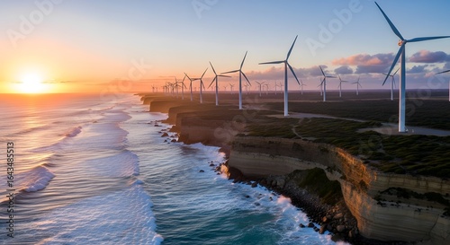 Wind turbines stand along a coastal cliff at sunset, generating renewable energy.