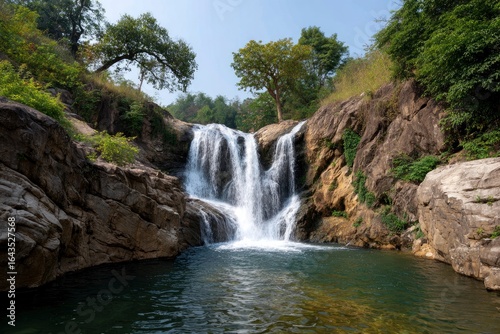 Waterfall cascading into a pool surrounded by rocks trees and sky