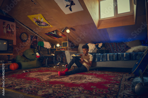 Photos Teen boy reading notebook in retro attic bedroom