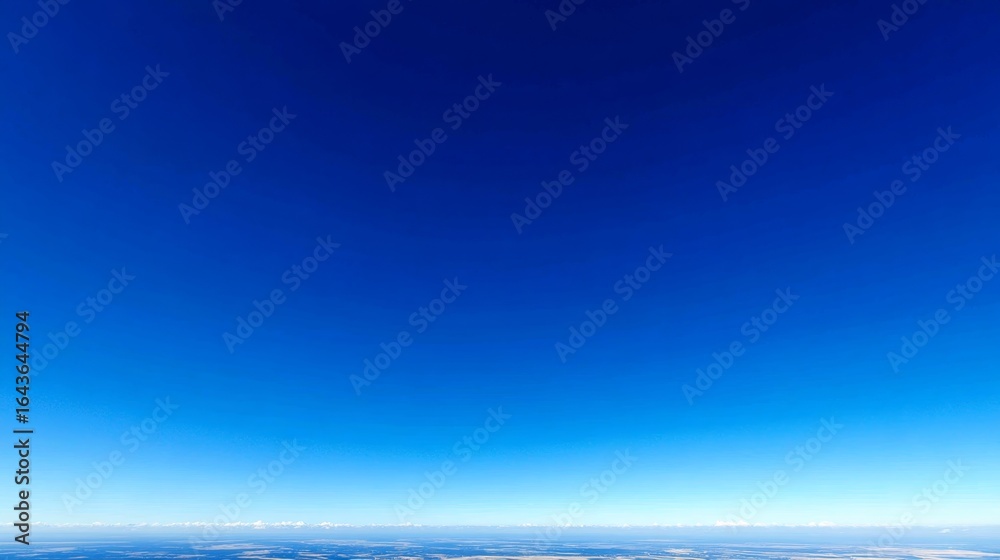 Fototapeta premium Lowangle shot of a vibrant blue sky with a gentle gradient from deep azure at the top to pastel sky blue near the horizon, creating a serene and expansive background with ample copy space on the righ