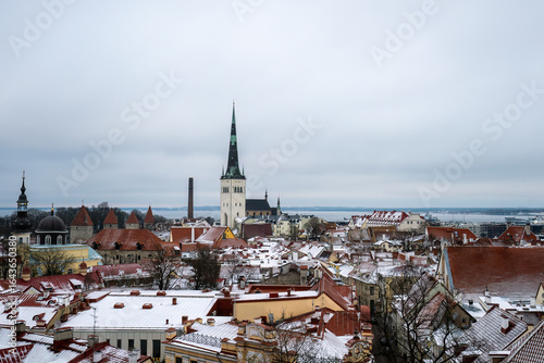 Winter panoramic view of snowy rooftops and St Olaf church in Tallinn old town