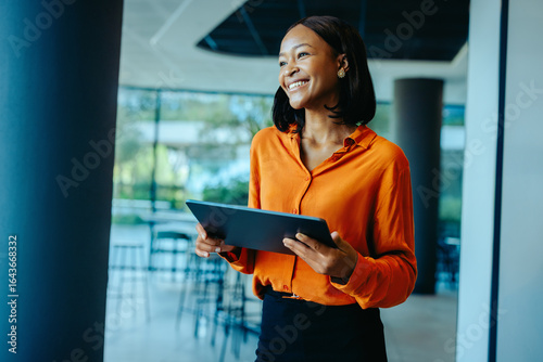 Cuadro en lienzo Confident African business executive using tablet in modern office setting