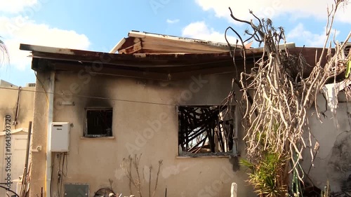 A burnt and destroyed house at a southern Israeli kibbutz, where a massive massacre was carried out. a slightly burnt, hardly alive bush plant is at the foreground. Kibbutz Nir Oz.