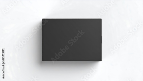 Top down view of a closed matte black rectangular box on a white surface with a soft shadow