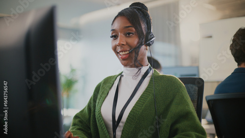 Canvastavla Confident African American female call center agent communicates with clients using headset and computer
