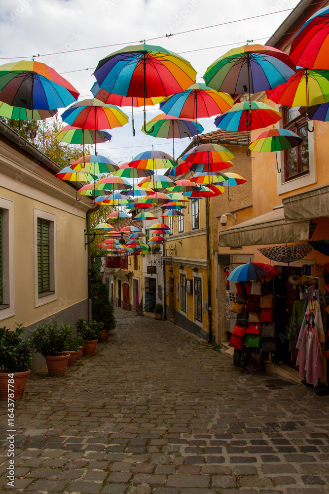 Fototapeta premium Colorful Umbrella Installation Over Narrow Cobblestone Street 