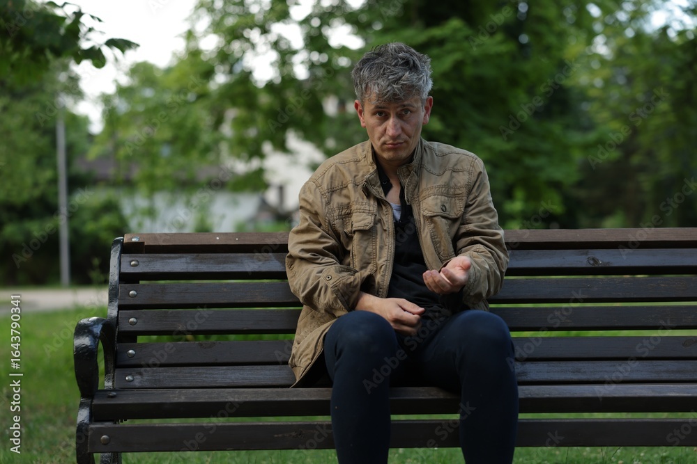 Obraz premium Homeless man begging for money on bench in park
