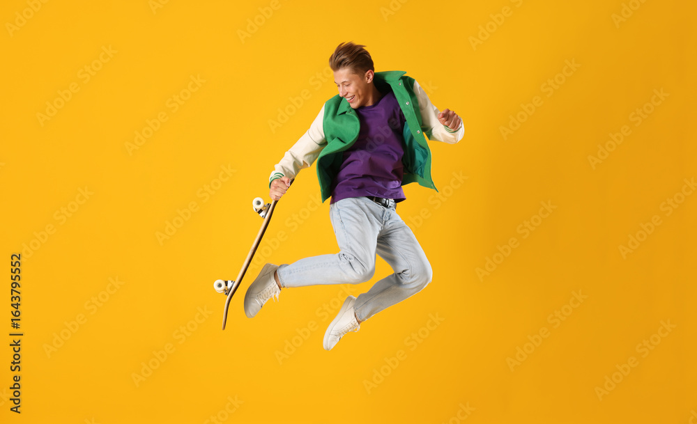 Fototapeta premium Man with skateboard jumping on orange background