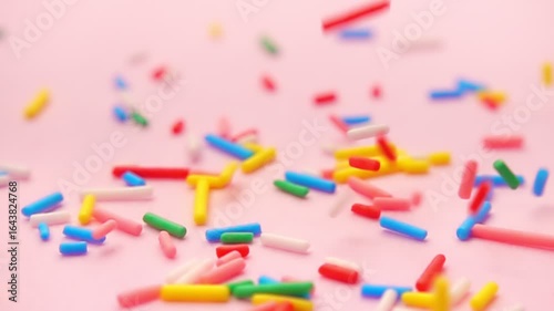 rainbow hued sprinkles descending softly against tranquil pink background, embodying spirit of joy and celebration, super slow motion