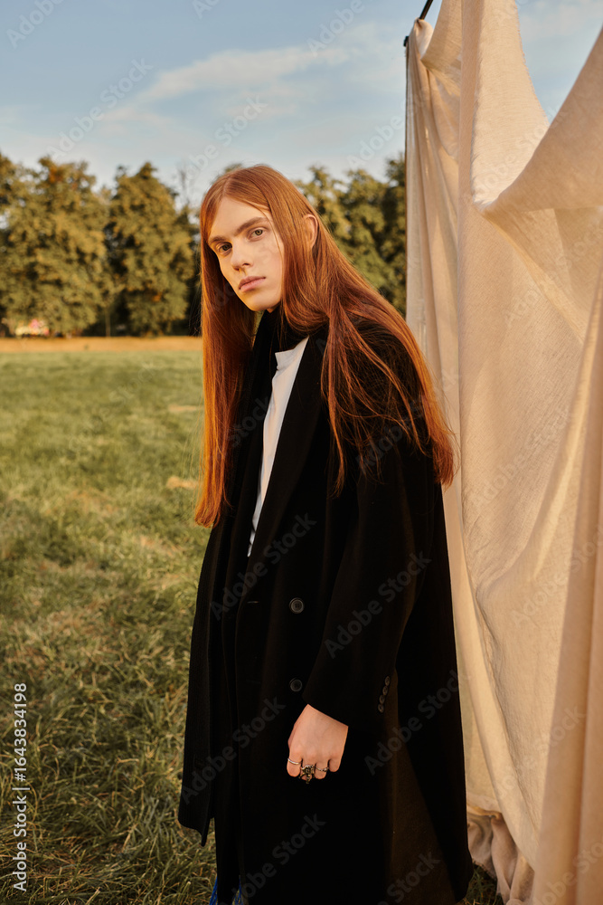 Naklejka premium Redhead young man in stylish autumn outfit outdoors during golden hour
