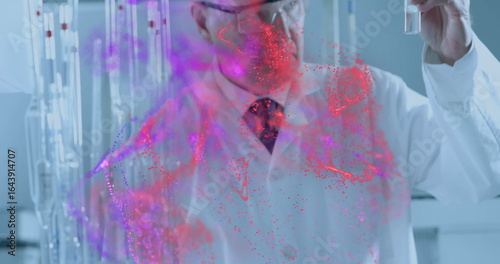 Inspecting researcher wearing lab coat holding test tube in lab viewing red magenta particle cloud