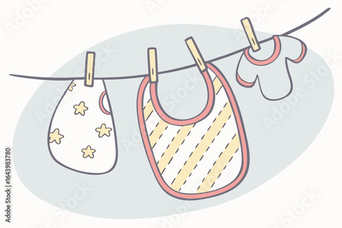 Baby bibs hanging on a string with mini clothespins, selective focus on one pastel print.