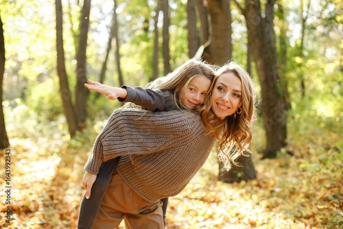 Fashionable young mother with a little daughter in autumn park