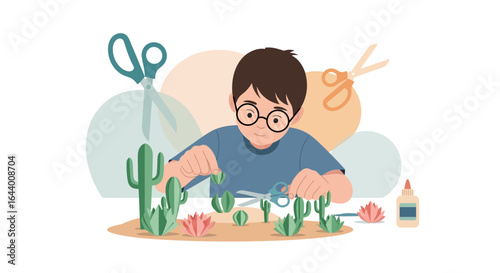 Boy crafts a miniature desert landscape from paper using scissors and glue at home