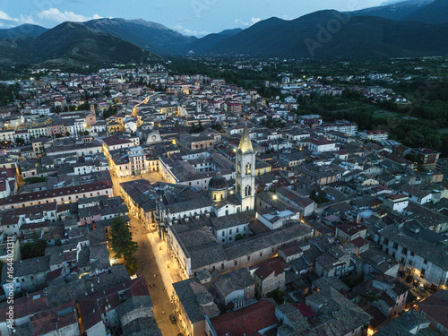 Aerial view of the magnificent Sulmona Cathedral and cityscape bask in the soft glow of twilight, nestled amidst rolling hills, Sulmona, Abruzzo, Italy.