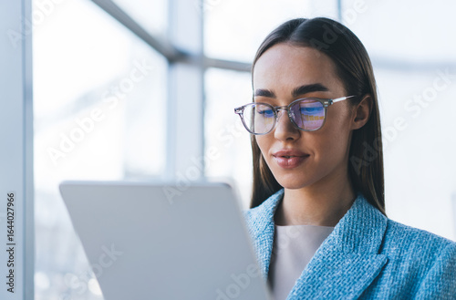 Obraz na plátně Close-up of focused freelancer with tablet, reflecting interface in glasses, symbolizing seamless connectivity, data immersion and digital harmony in professional interaction