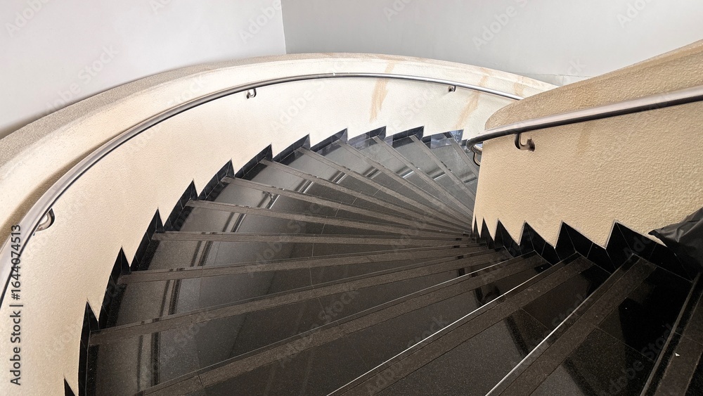 Fototapeta premium Modern Spiral Staircase with Black Granite Steps and Cream Walls.