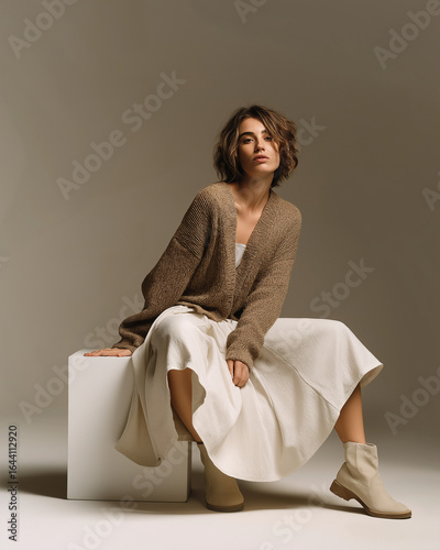 woman in neutral outfit sitting on cube