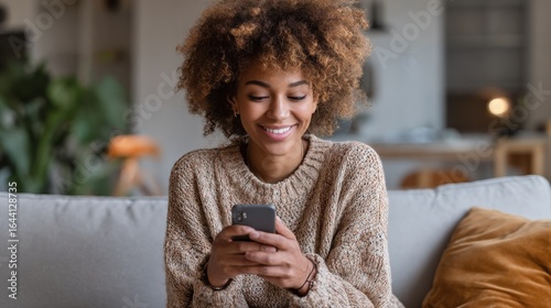 smiling afro american millennial woman user holding smart phone watching video playing game shopping chatting in mobile technology application sitting on sofa at home close up view banner design no l