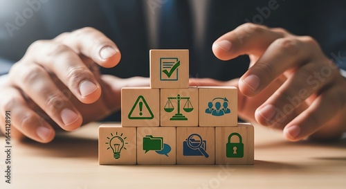 Hands protecting wooden blocks with business and legal icons symbolizing security and risk management