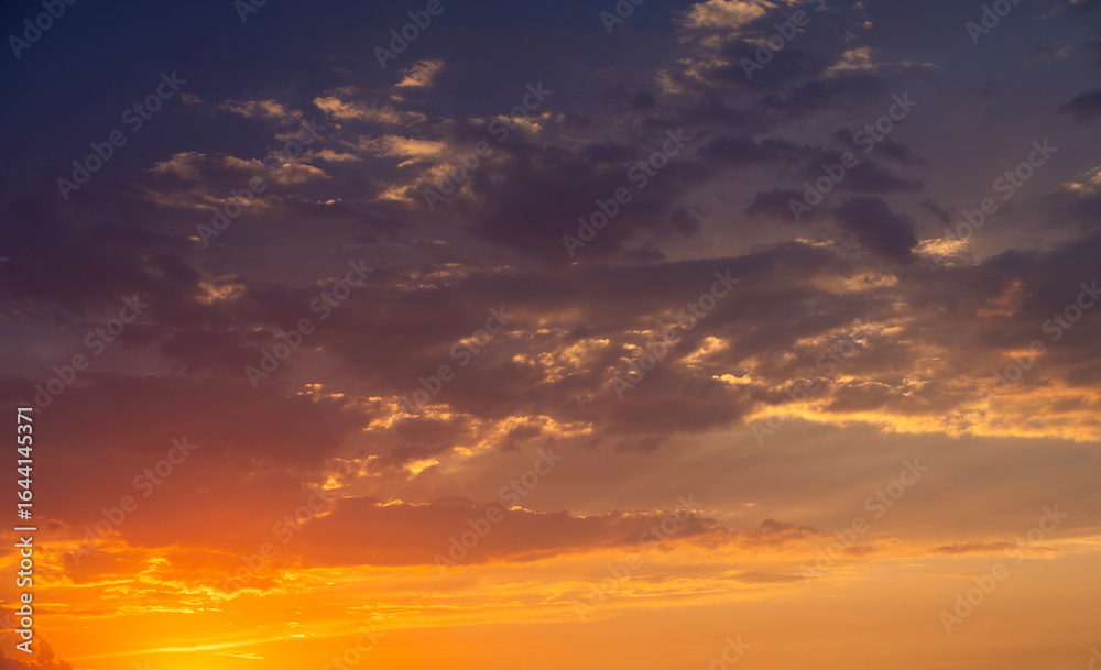 Fototapeta premium Bright orange sunset sky background with dramatic clouds. 