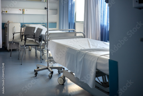 Interior of a vacant hospital room, featuring two adjustable beds, chairs, and medical equipment. A quiet and orderly scene that symbolizes the healthcare industry, insurance, and patient recovery.	