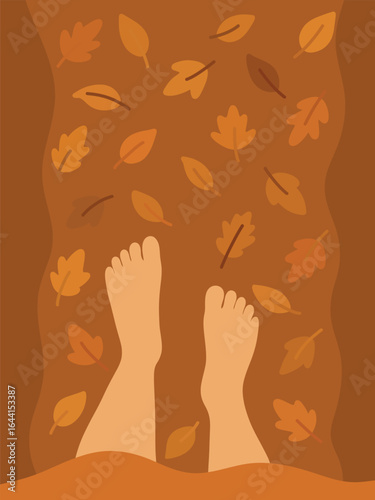 Top view of bare feet walking on a forest trail covered in colorful autumn leaves.
