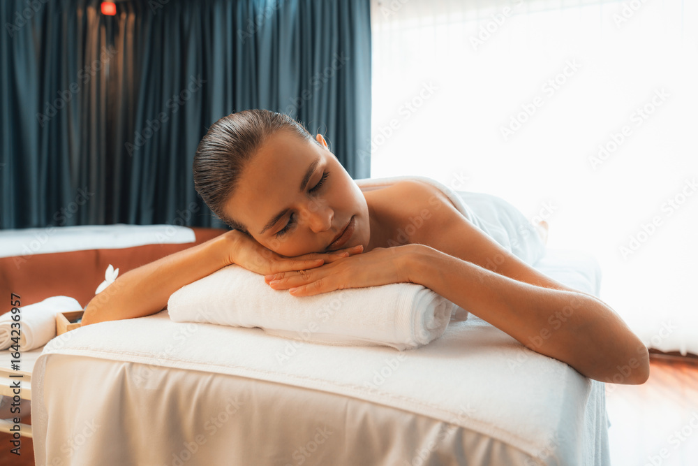 Obraz premium Caucasian woman customer enjoying relaxing anti-stress spa massage and pampering with beauty skin recreation leisure in day light ambient salon spa at luxury resort or hotel. Quiescent