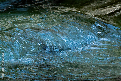 Water flows over ice in a rapids of the Sugar River in Newport, New Hampshire in winter.