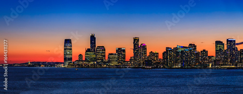 Jersey City skyline silhouette from New York, dramatic sunset over Hudson River