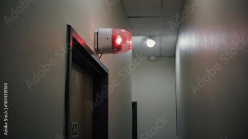 Red Siren Light Flashing in a Hospital Hallway with Gray Wall and Wooden Door Frame