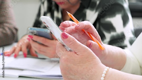 Elderly hands holding mobile phone, learning technology in retirement group. 
