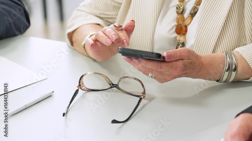 Older adults discovering digital tools. Mature woman in jewelry using smartphone, elderly learning modern gadgets.