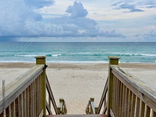 wooden pier on the beach with waterspout out at sea