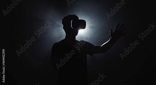 Silhouette of a man wearing VR headset with outstretched hand