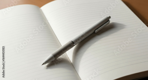 Wallpaper Mural Minimalist concept of writing, journaling, or studying with a pen resting on a blank open notebook on a wooden table. Torontodigital.ca