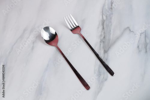 Metal spoons and forks on a marble table. Asian tableware.