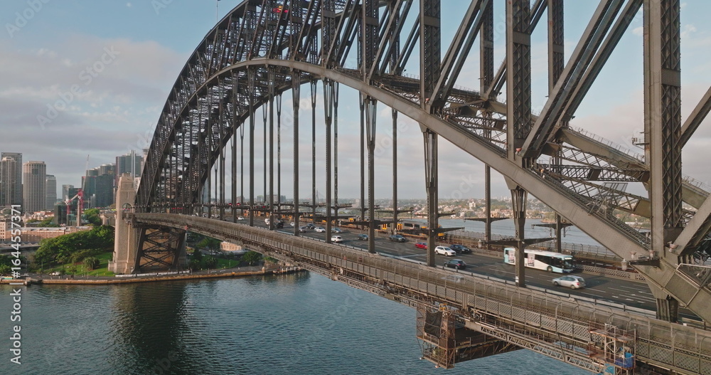 Australia, Sydney: Cars and buses driving Sydney Harbour Bridge during sunny morning rush traffic hour in city center, travel destination, modern city architecture skyline in background. Aerial view Australia, Sydney: Cars and buses driving Sydney Harbour Bridge during sunny morning rush traffic hour in city center, travel destination, modern city architecture skyline in background. Aerial view