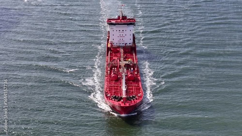 Aerial footage of a large red freighter ship slicing through the water in The Netherlands