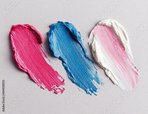 Pink, blue, white cosmetic swatches on gray background