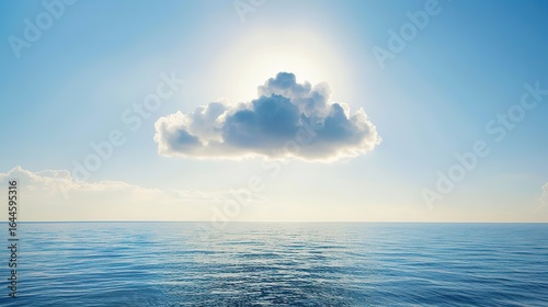 A single cloud shadow stretches over the calm ocean under bright sunlight; the sun shines warmly, the sky is clear and blue, the water's surface is smooth and still, and the interplay of light and sha
