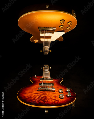 Two electric guitars in a mirrored image.  One a gold top with P90 pickups and one a flame top with humbucker pickups 