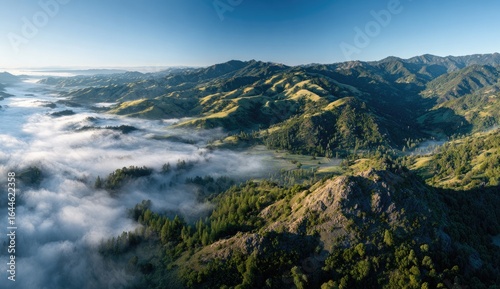 Wallpaper Mural Panoramic sunrise view of rolling hills and valleys cloaked in morning mist, showcasing diverse vegetation and a rocky peak in the foreground Torontodigital.ca