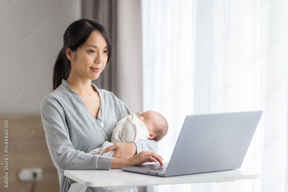 Mother caring baby while working on laptop Mother caring baby while working on laptop