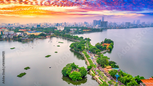 Fototapeta Naklejka Na Ścianę i Meble -  Aerial view of road crossing the island Westlake, Hanoi, Vietnam with green tree lined street, temple located between small oasis. A beautiful sunset in capital of Vietnam